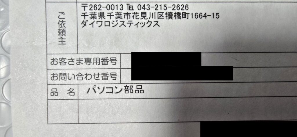 無地ダンボールに貼られたNLSの送り状。品名欄はパソコン部品、依頼主はダイワロジスティックス